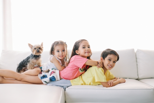 three siblings lying on sofa 1 boy two girls with cute dog