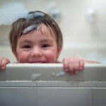 portrait of little baby with bubbles in bath tube